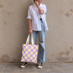 Woman standing in jeans and a white shirt with the purple yellow checkered tote bag