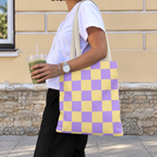 Woman carrying the purple yellow checkered tote bag on her shoulder while holding a drink