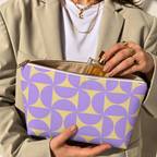 Woman holding the purple yellow geometric makeup bag open with the gold zipper