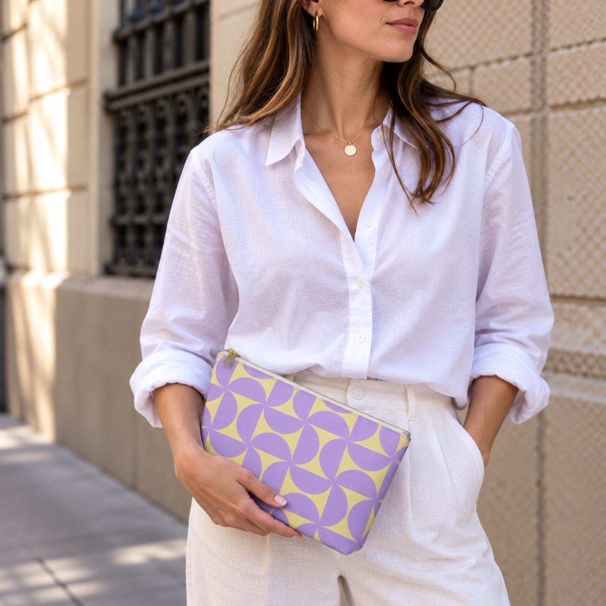 Woman in a white shirt holding the purple yellow geometric makeup bag as a clutch