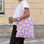 Woman carrying the purple yellow geometric tote bag on her shoulder while holding a drink