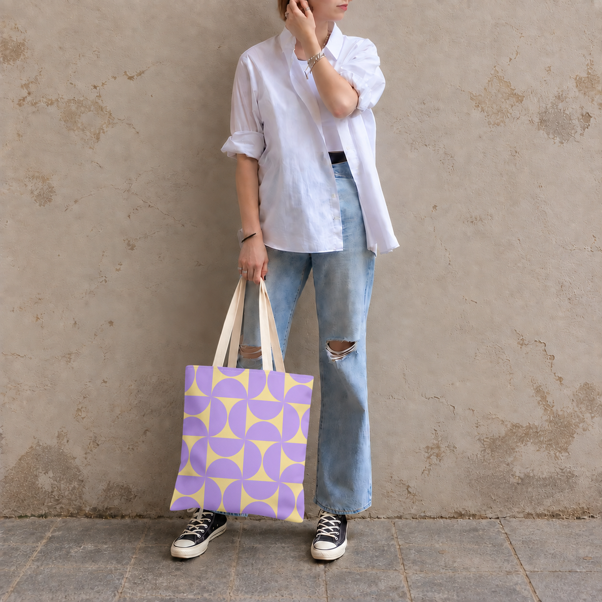 Woman standing in jeans and a white shirt with the purple yellow geometric tote bag