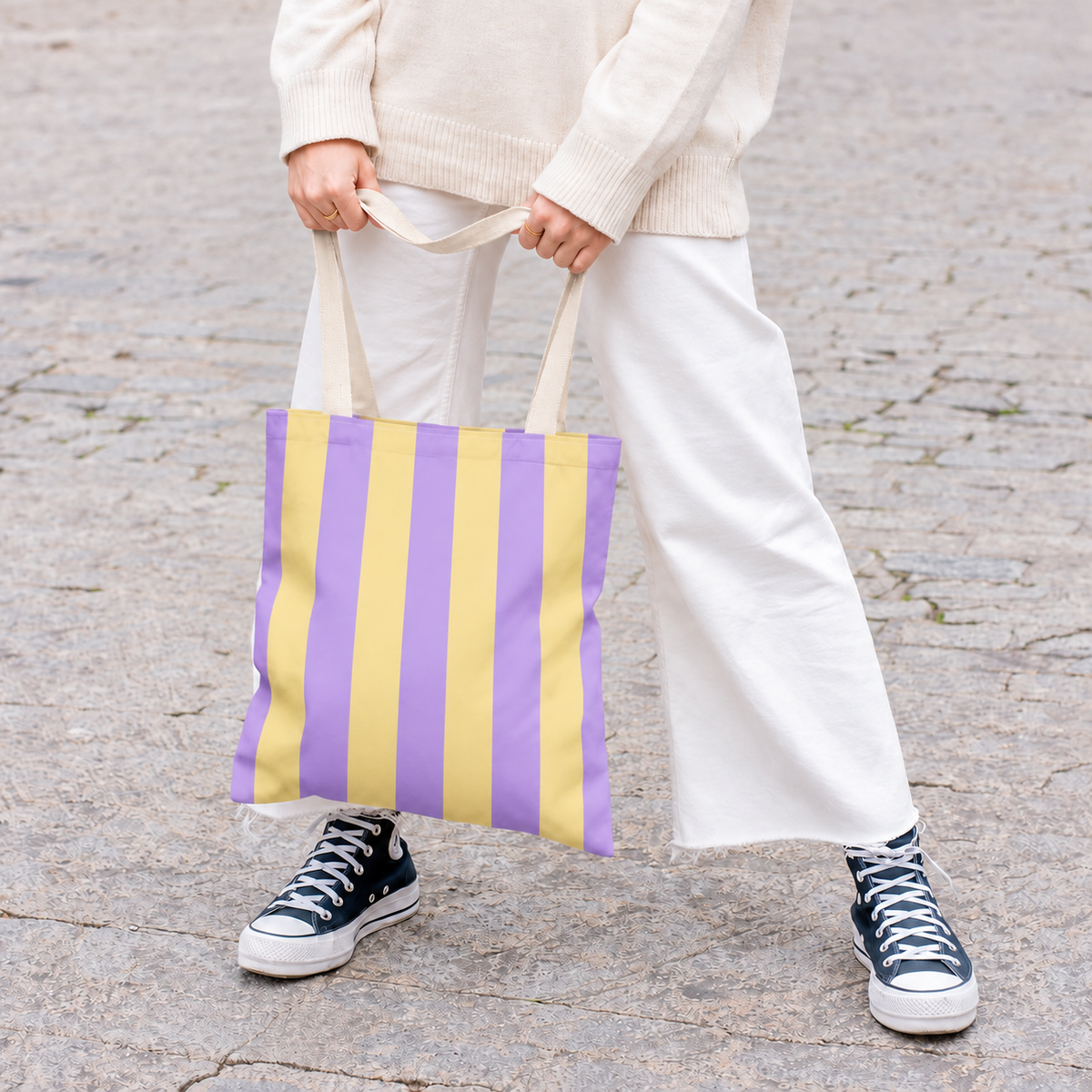 Model in white trousers carrying the Purple Yellow Striped tote bag