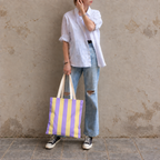 Full-length model photo with the Purple Yellow Striped tote bag against a wall