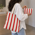 Woman wearing the red cream striped tote bag with the matching makeup bag in her hand