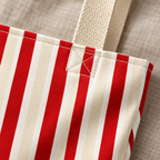 Close-up of the bright red and cream stripes and the beige handle on the red cream striped tote bag