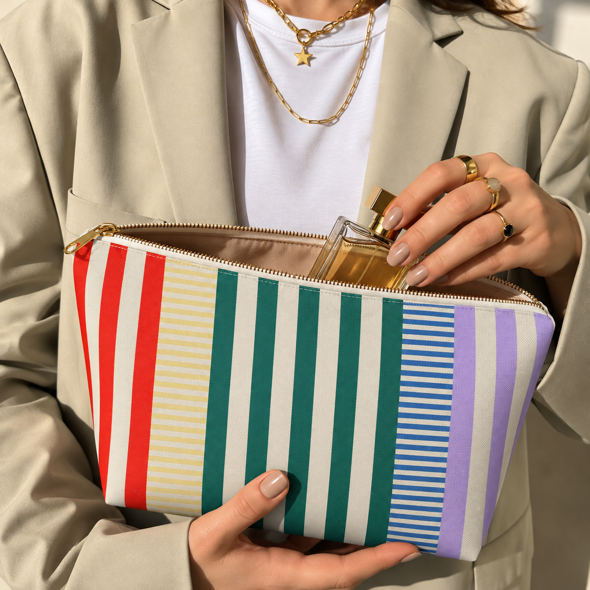 Woman holding the striped makeup bag open with a perfume bottle inside