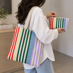 Woman carrying the striped tote bag on her shoulder next to the matching makeup bag