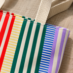 Close-up of the red, cream, green and blue stripes and cream handle of the striped tote bag