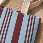 Close-up of the sky blue and burgundy stripes with beige handle on the tote bag